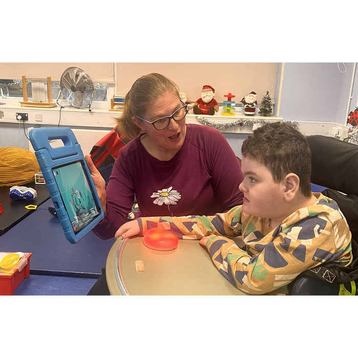 Student using a Cosmo Dot wireless switch with an iPad during a classroom activity